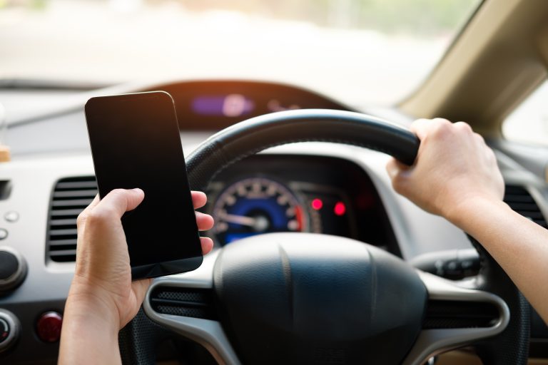 person driving holding their cell phone